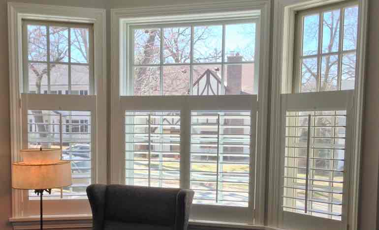 Bottom half white shutters in living room bay window.